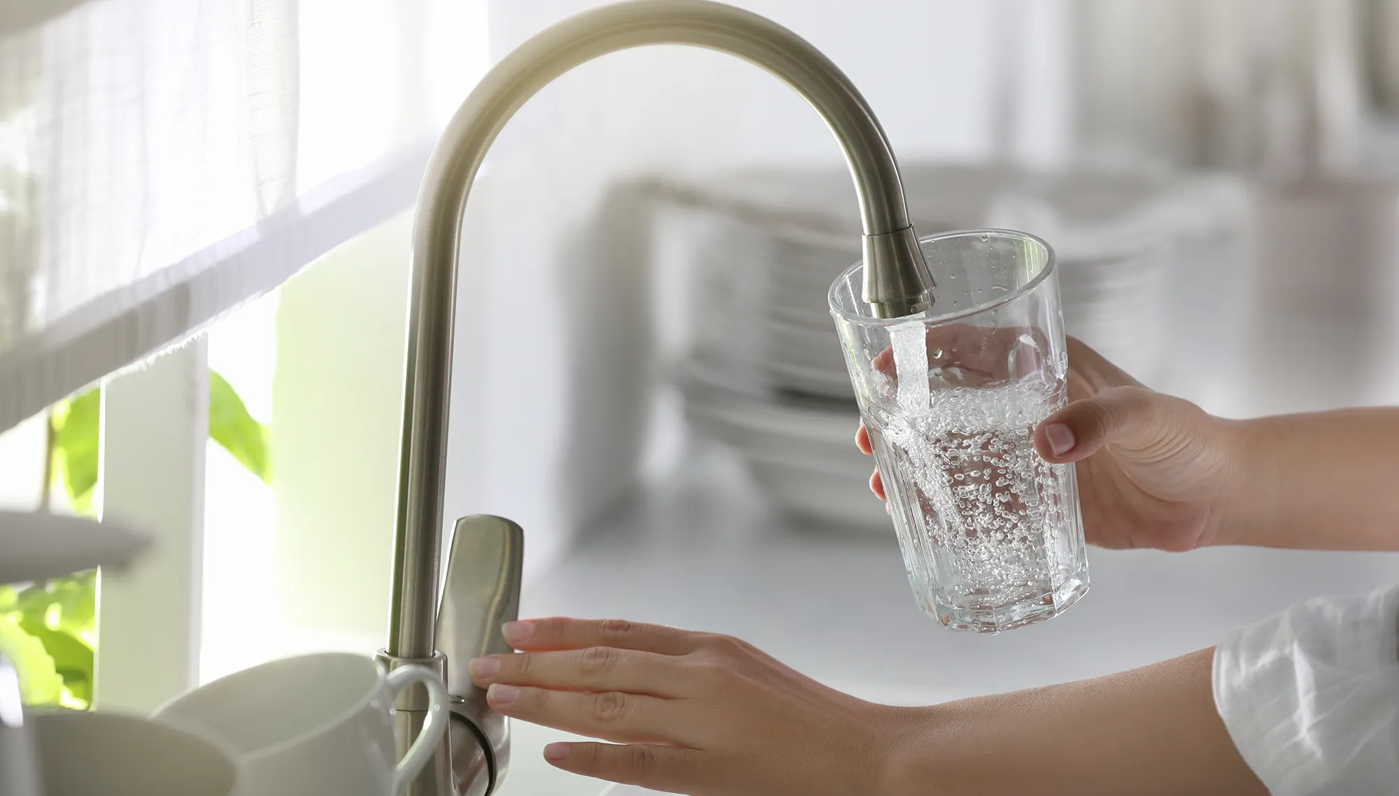 Frau füllt ein Glas mit Trinkwasser