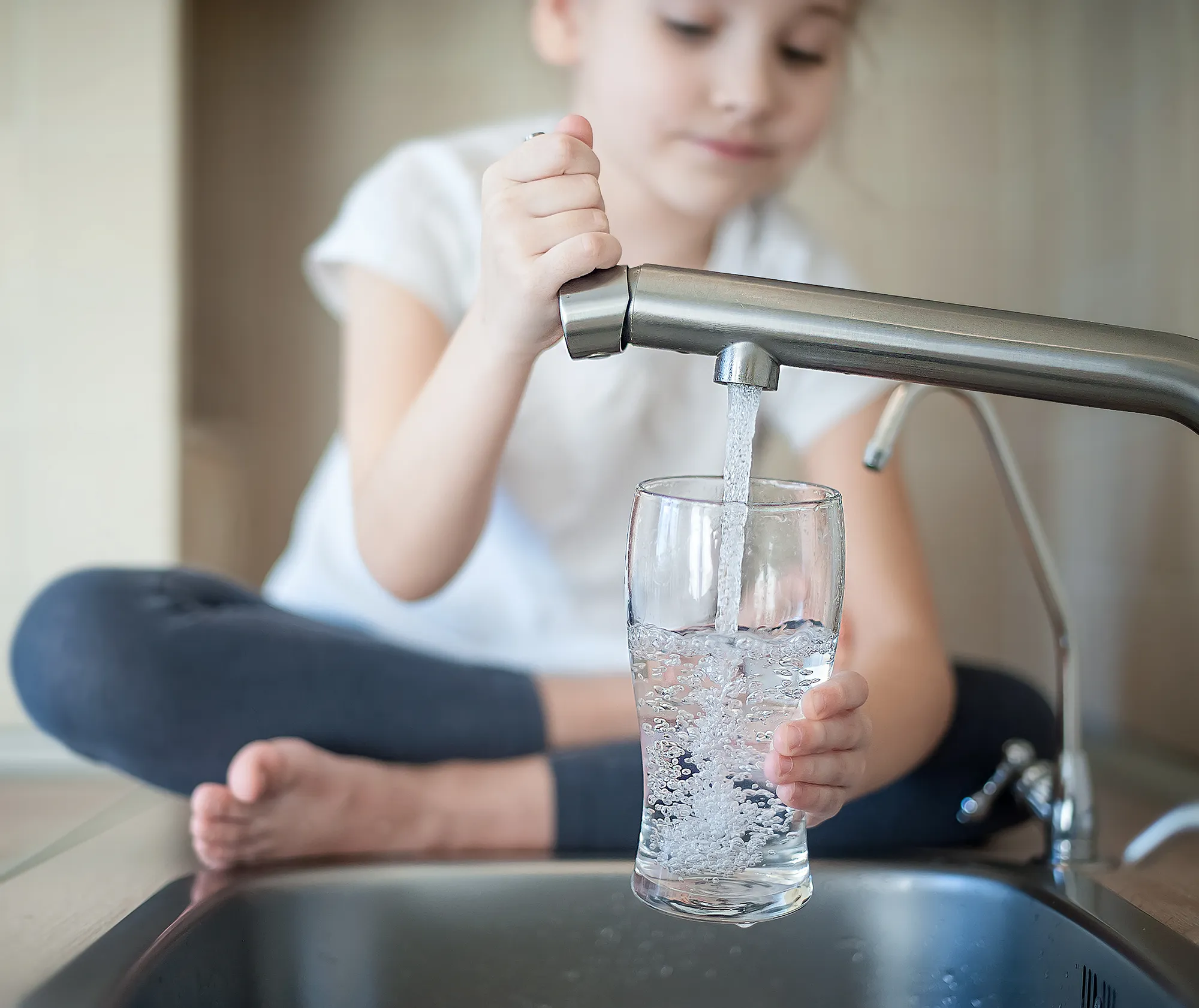 Junges Mädchen schenkt sich ein Glas Wasser ein